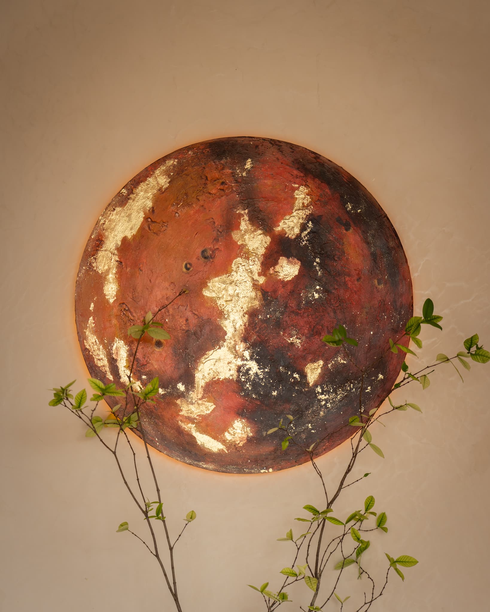 The MARS house artwork: a textured painting of Mars finished with gold leaf, hanging on the lime-washed wall